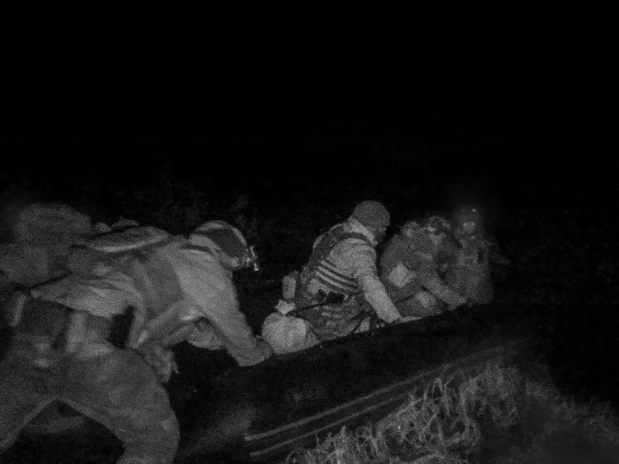 Члени бригади штовхають човен у воду Дніпра. Ця фотографія була зроблена за допомогою апаратури нічного бачення.
